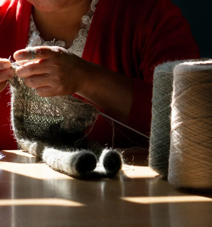 Mani di un’artigiana che lavora a maglia
